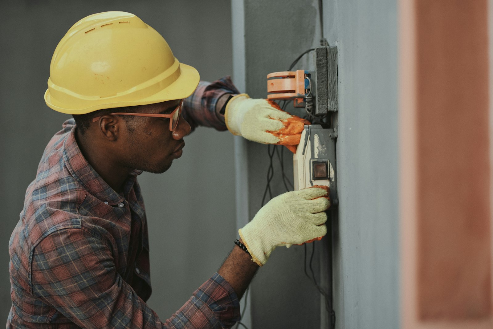 Electrician in a hard hat installing equipment on a job site